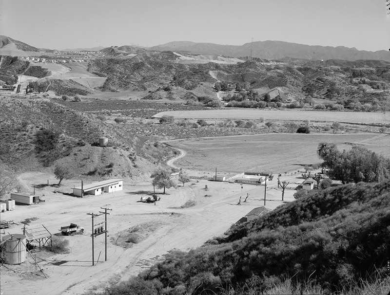 GENERAL VIEW OF ADOBE STABLES, WITH MISCELLANEOUS OUTBUILDINGS TO LEFT (WEST) AND TO RIGHT NEAR SWIMMING POOL (EAST); CAMERA FACING NORTHEAST